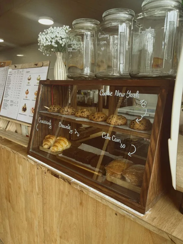 Tủ bánh gỗ trên quầy: Cookie New York, croissant, brownie và cake cam